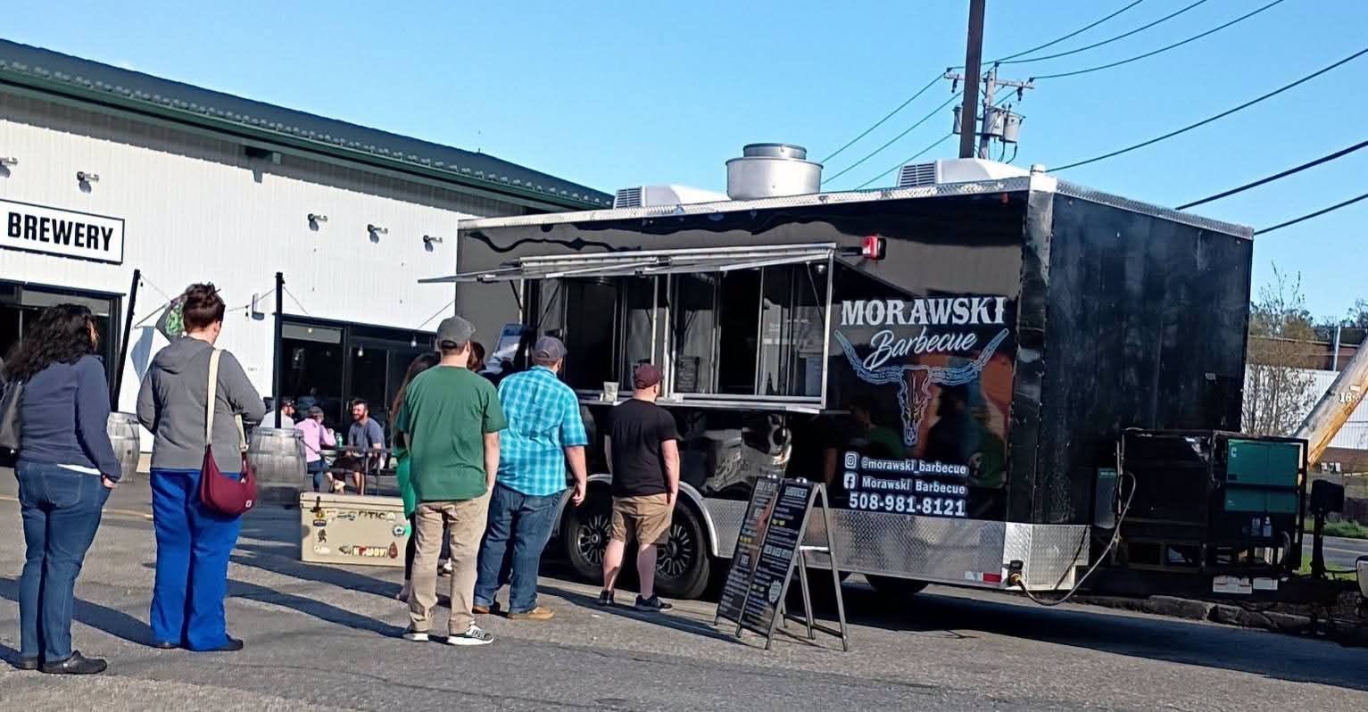 Catering spread on a long table with brisket, ribs, pulled pork, sides, and sauces